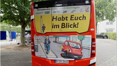 Rückseite von einem roten Linienbus mit einer Zeichnung. Darüber steht "Habt Euch im Blick""