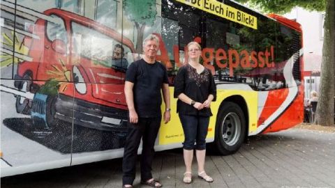 Wilfried Küfen der Künstler des Bildes und Annette Gnidowski stehen vor dem Bus mit dem Bild. 