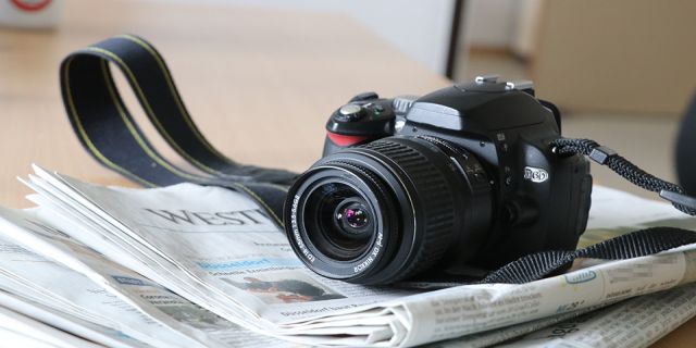 Eine Kamera liegt auf einem Stapel Zeitungen. 