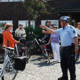 Mehrere Personen stehen mit ihren Fahrrädern um einen Polizisten. 
