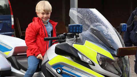 Ein Junge sitzt auf einem Polizeimotorrad. 